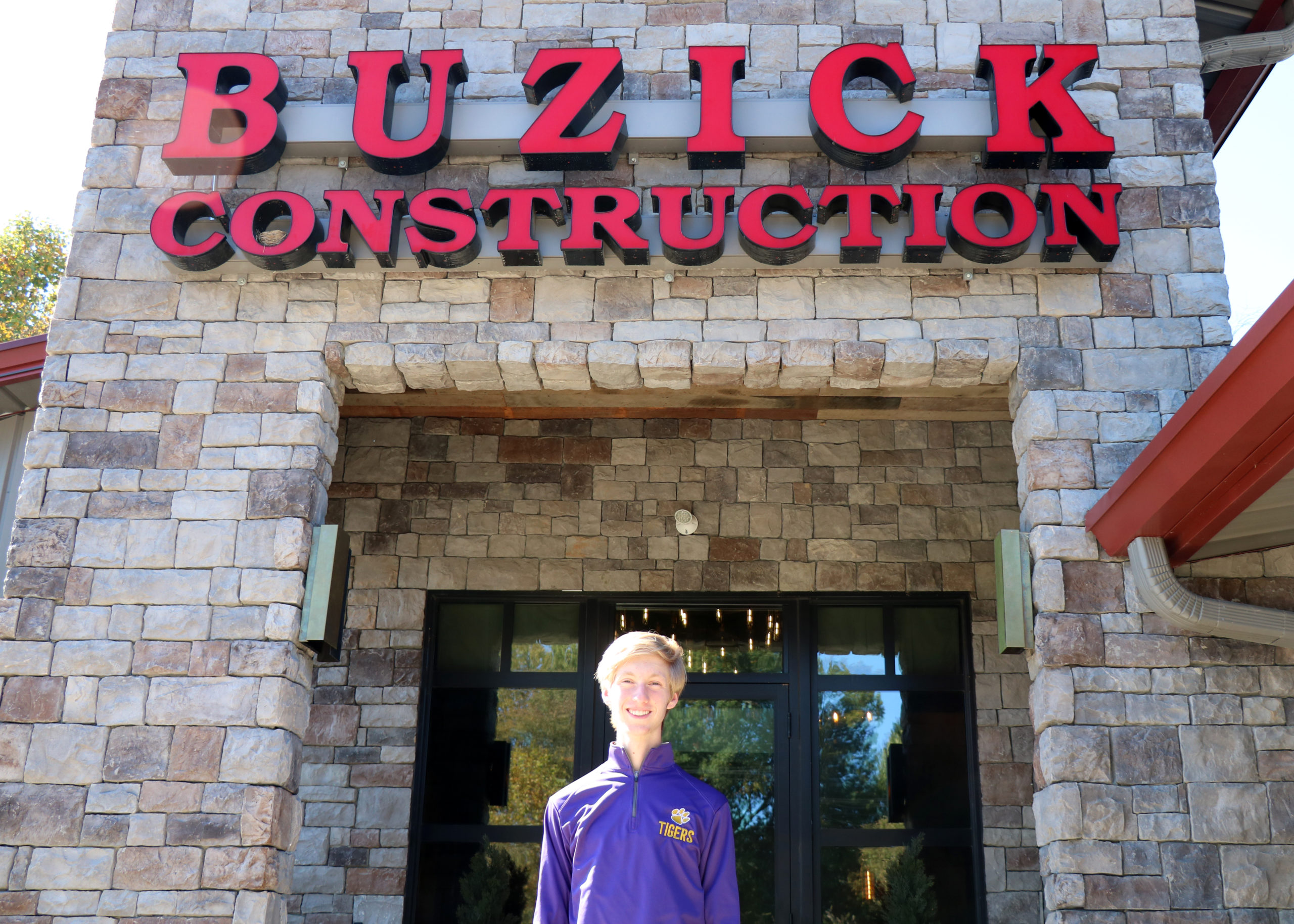 Eli Hill stands in front of Buzick Construction