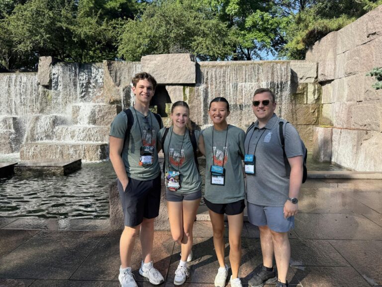 Students pose in front of a water fountain.