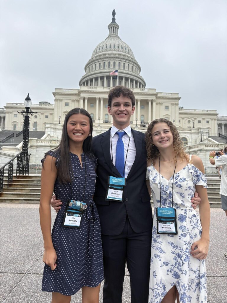 Three students stand in front of the national Capitol.