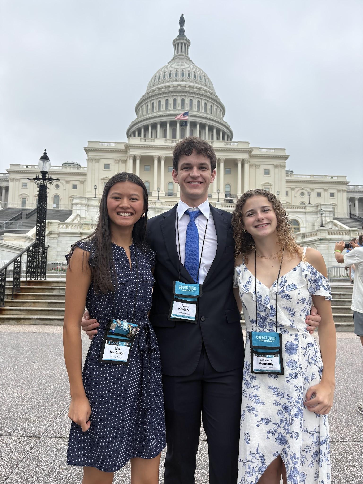 Three students stand in front of the national Capitol.