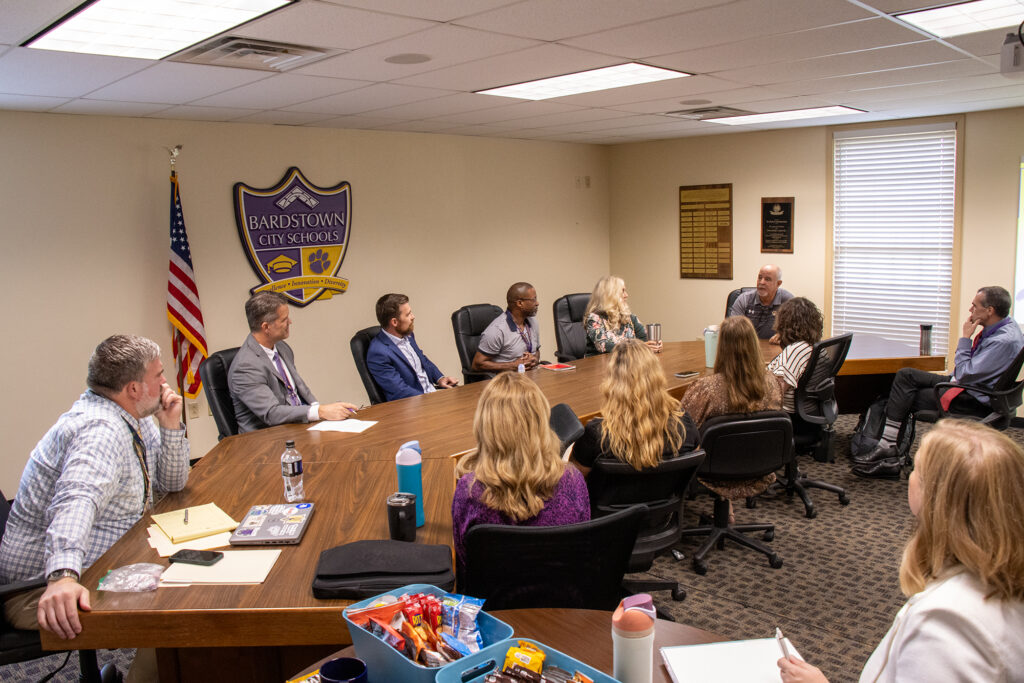 Group of people gather around a large table.
