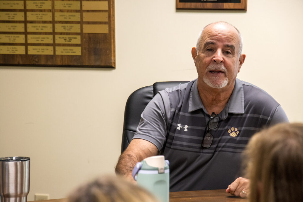 Man in gray polo talks to a group of educators.