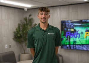 Logan Lanham wearing a dark green Norton Healthcare polo in the lobby of the Bardstown Polytechnic Center.