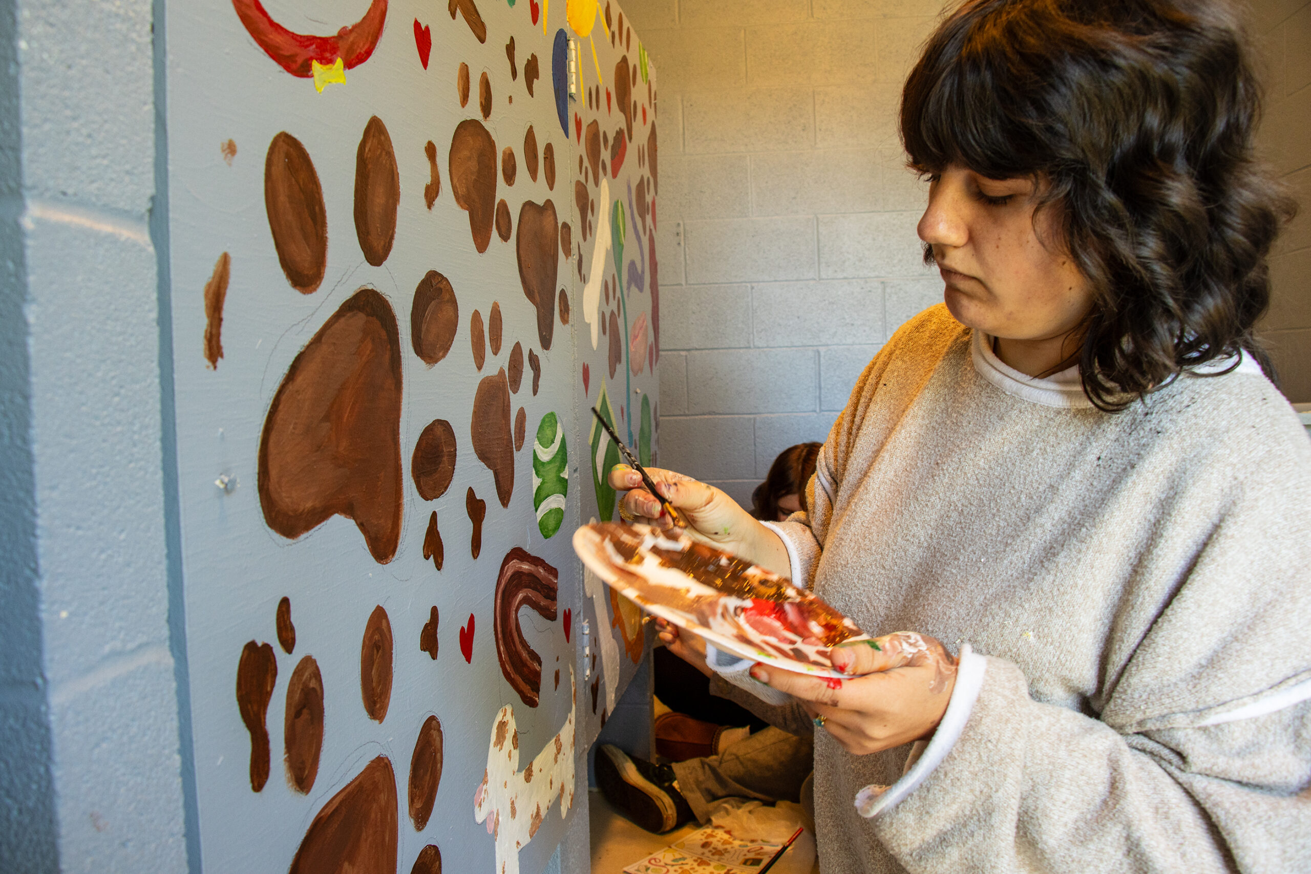 Alexandria Colwell working on the bathroom mural.