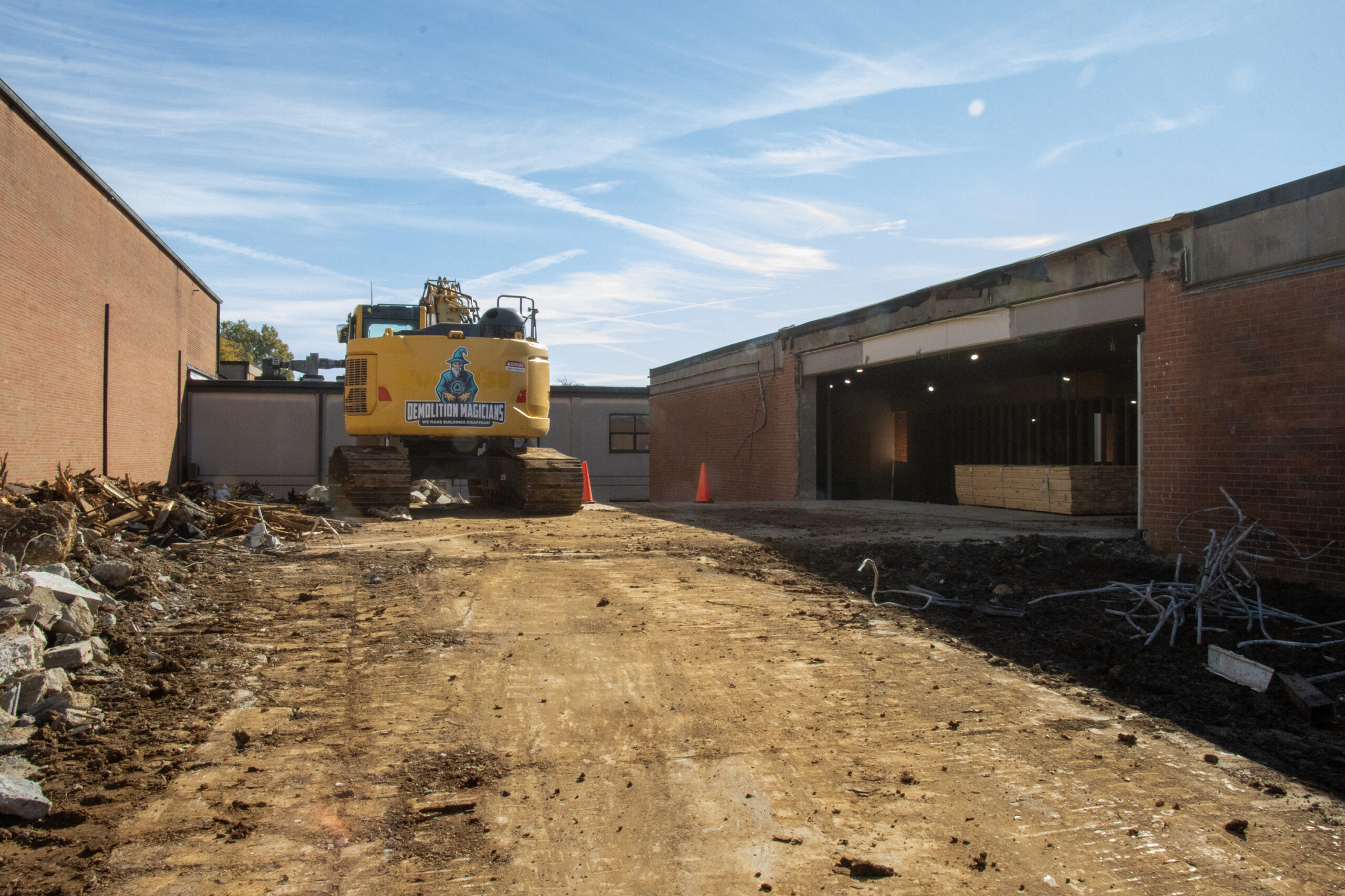 yellow bulldozer stopped on dirt near a brick building