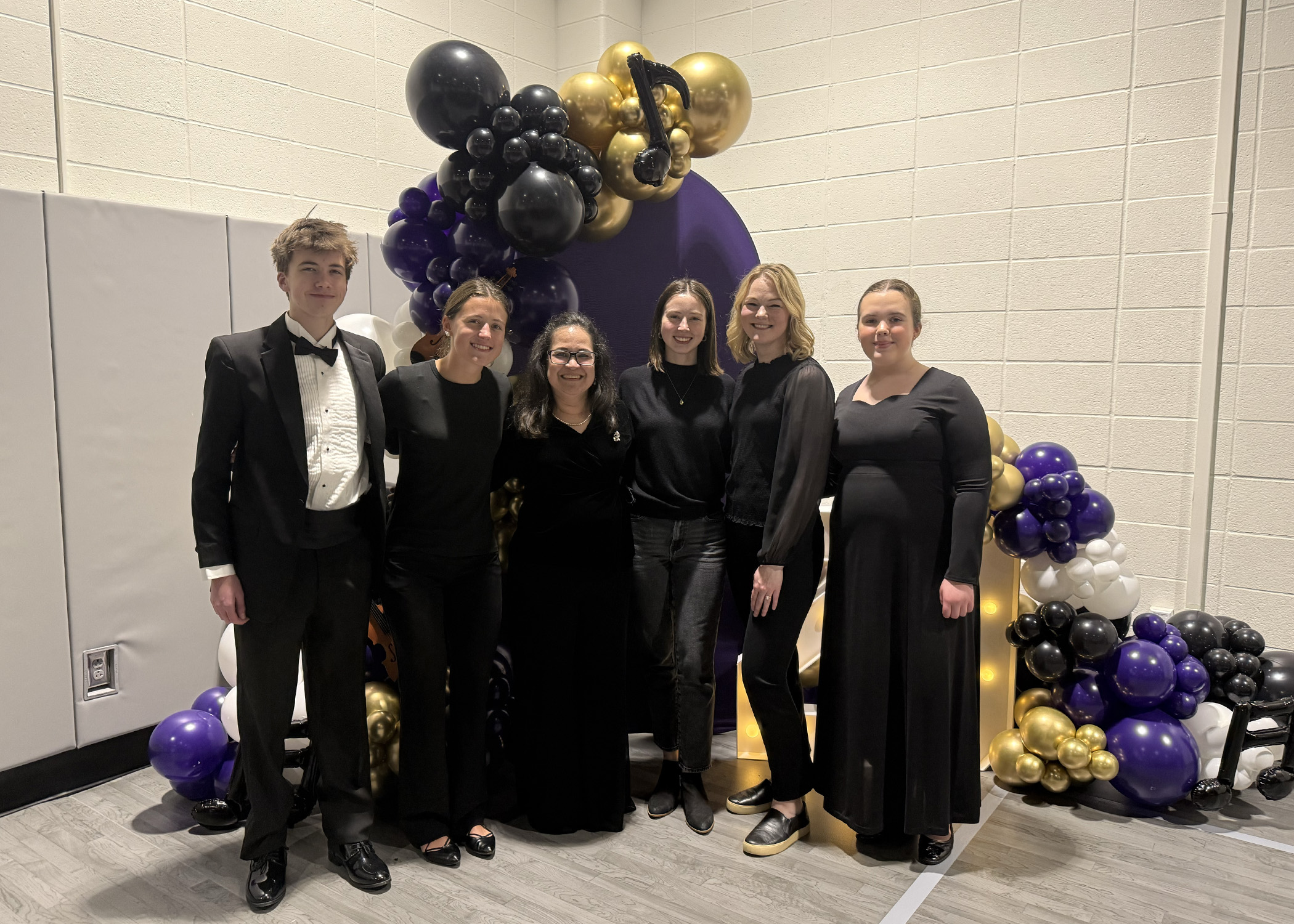 Mrs. Land poses with several members of the Walton family who have participated in the Strings program.