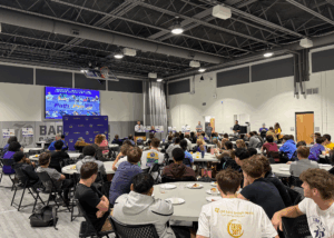 large gray room with tables, monitor and students