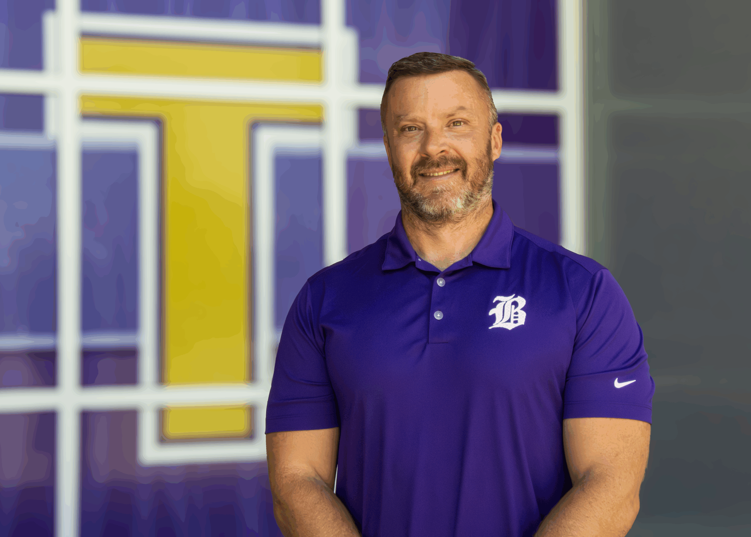man in purple polo stands in front of the cafeteria windows