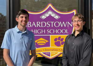 one person in blue shirt and another person in a long sleeve black shirt stand in front the high school.